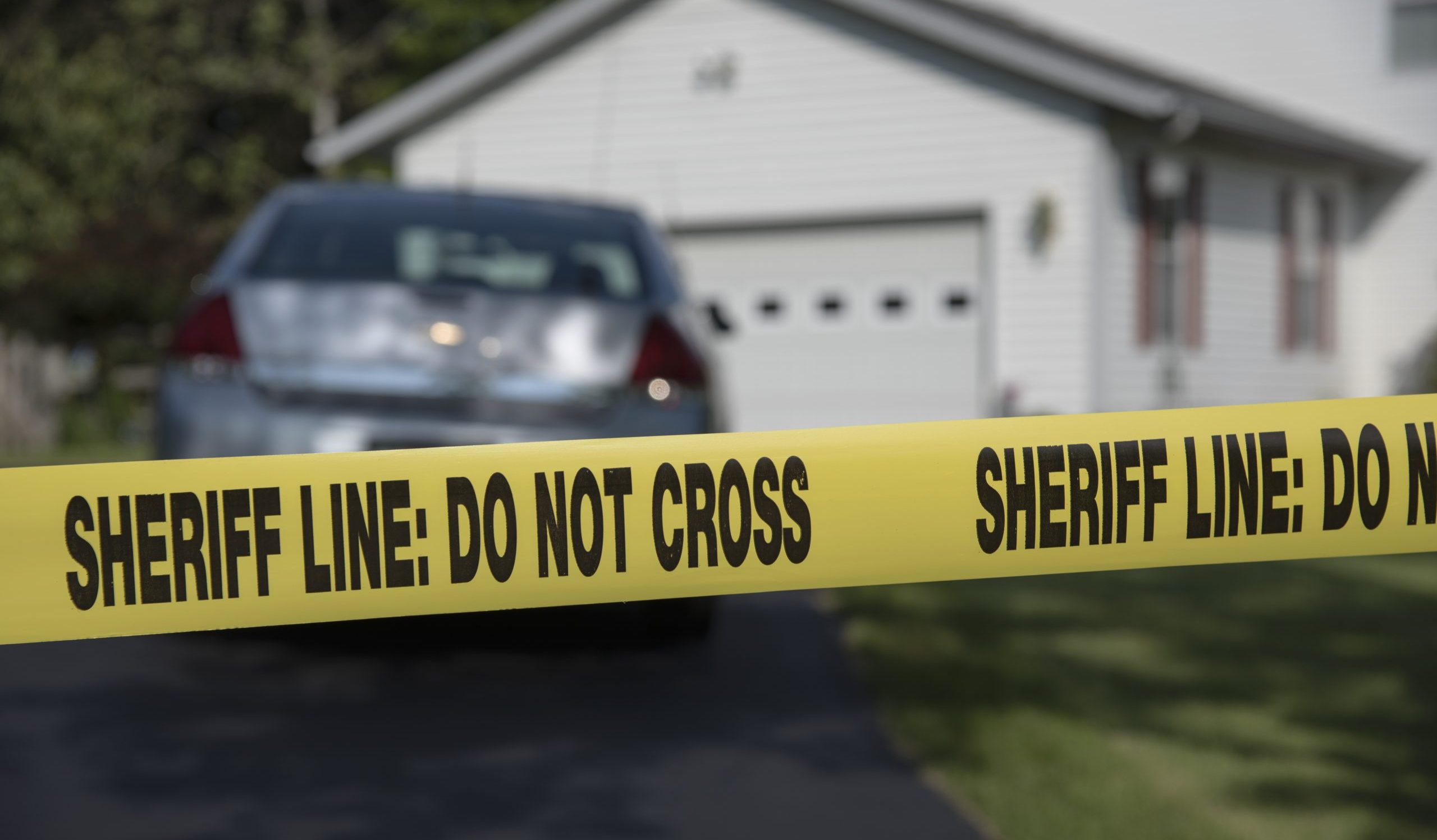 police tape in front of driveway and house