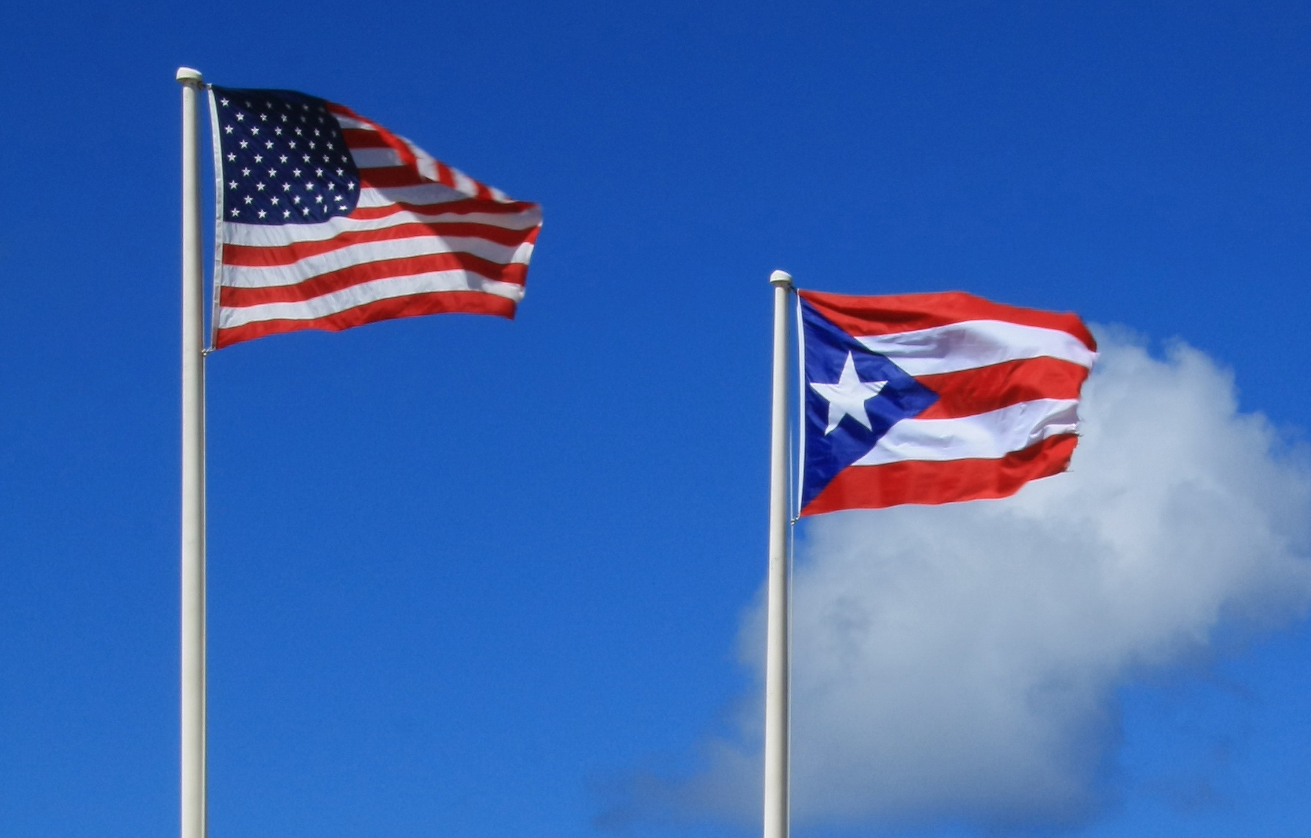 American flag and Puerto Rico flag against blue sky