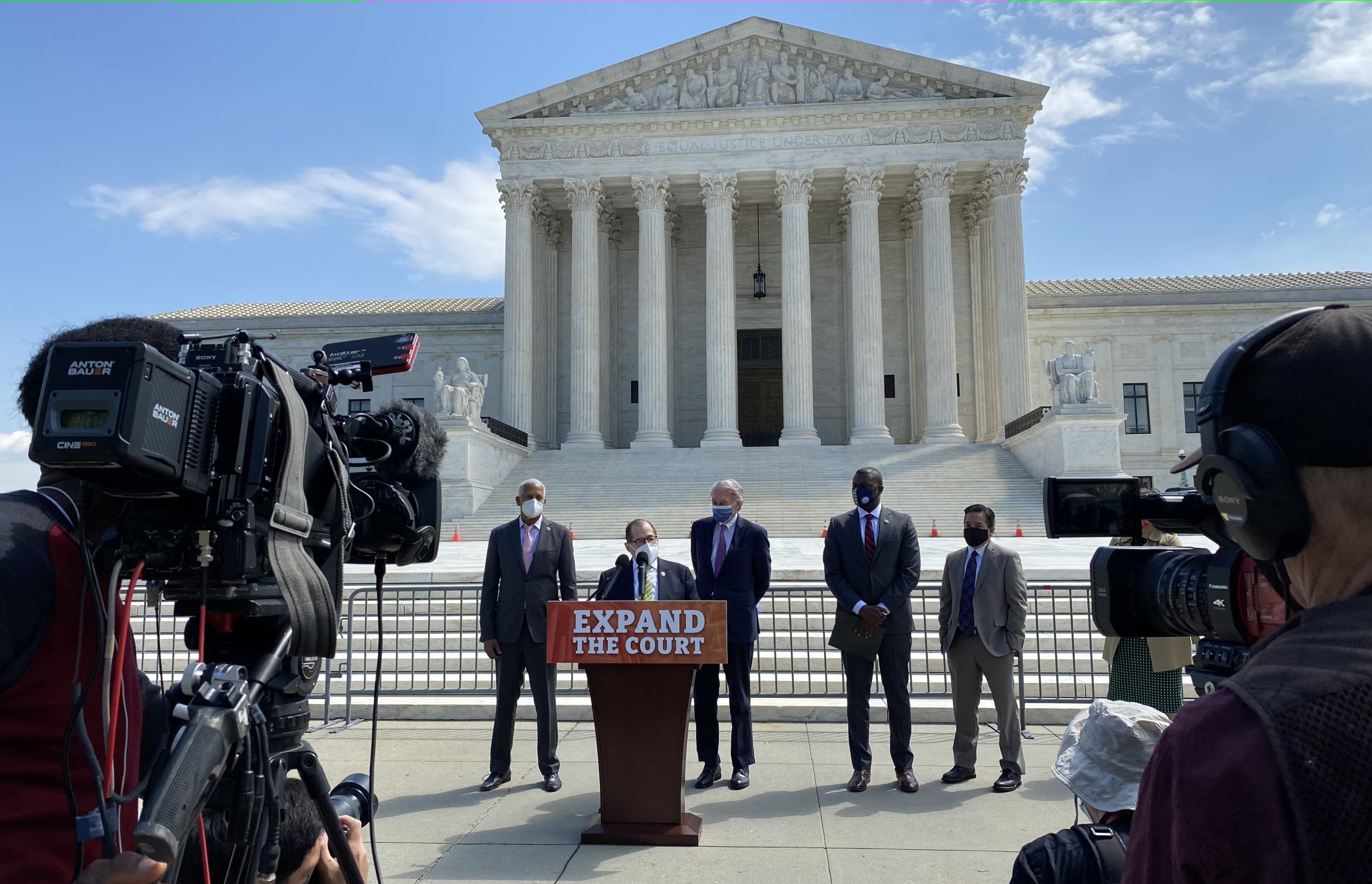 Rep. Jerrold Nadler, surrounded by other lawmakers, speaking at lectern with Supreme Court in background.