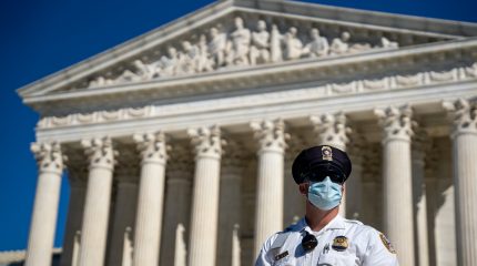 police officer in mask standing in front of supreme court building
