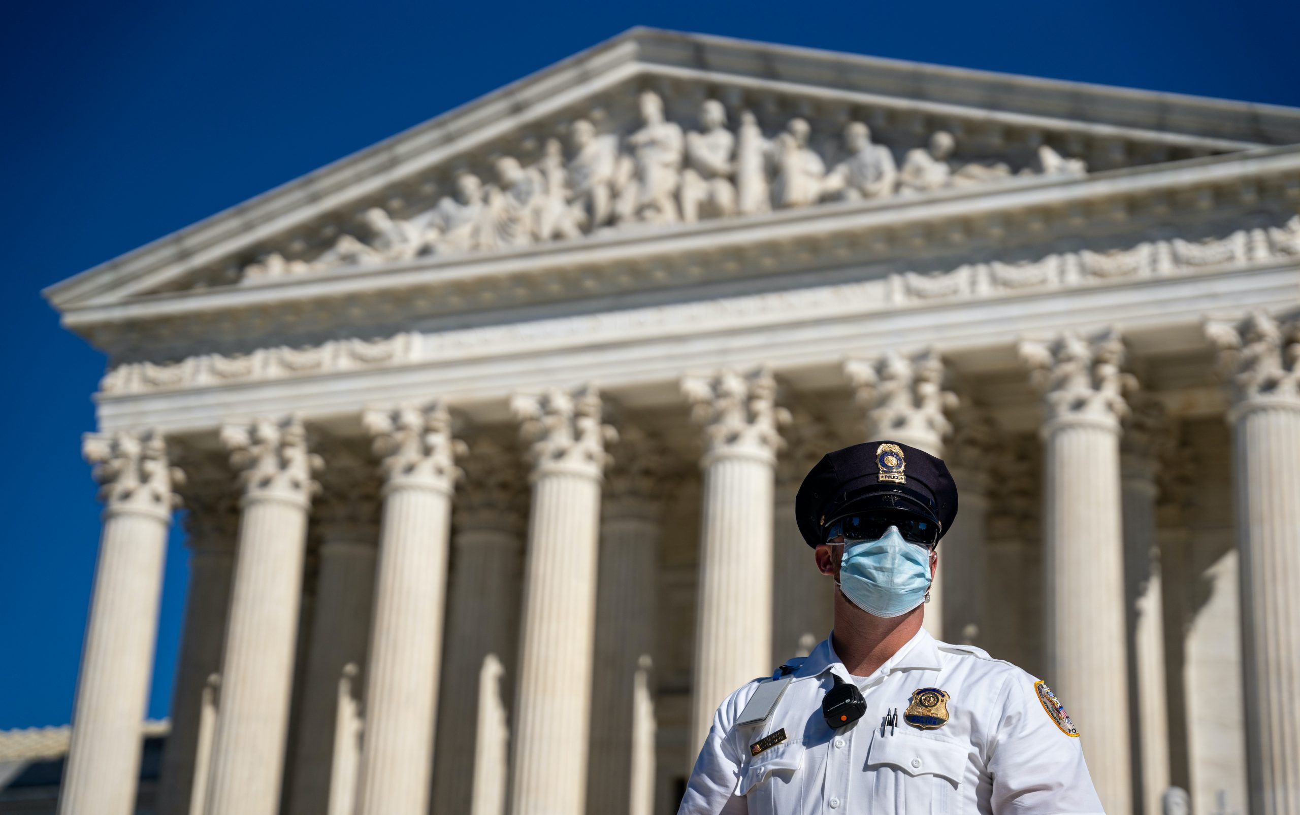 police officer in mask standing in front of supreme court building