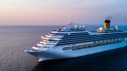 large cruise ship sailing in calm ocean water at sunset