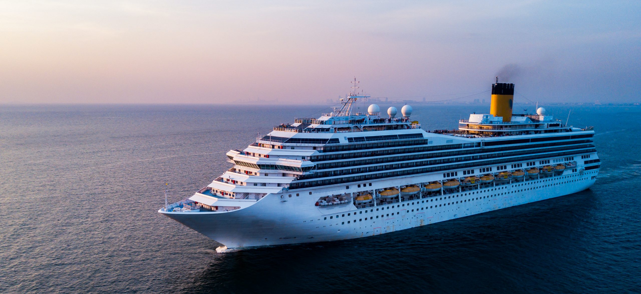 large cruise ship sailing in calm ocean water at sunset