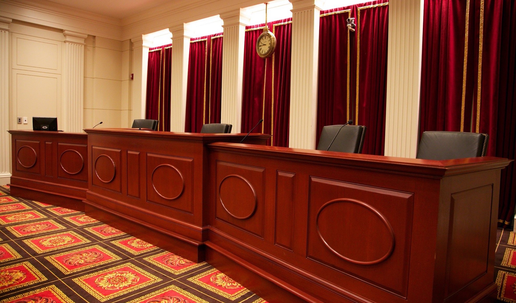 large wood-paneled judges' bench with four chairs