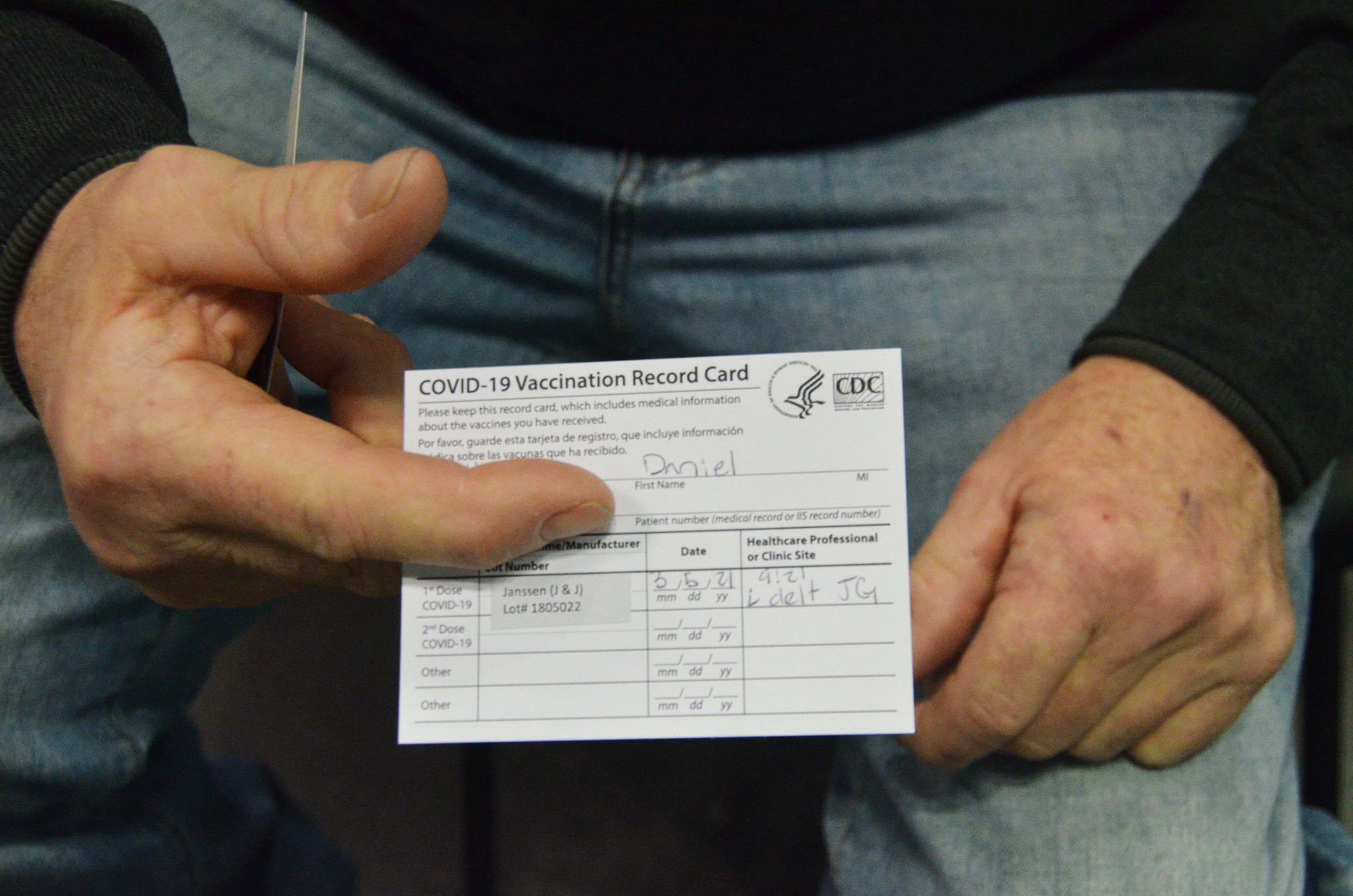 close up photo of man's hands holding vaccine card