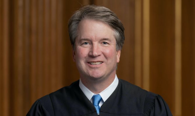 brett kavanaugh wearing judicial robe and sitting with hands crossed in lap