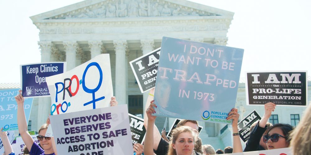 women holding signs in front of Supreme Court