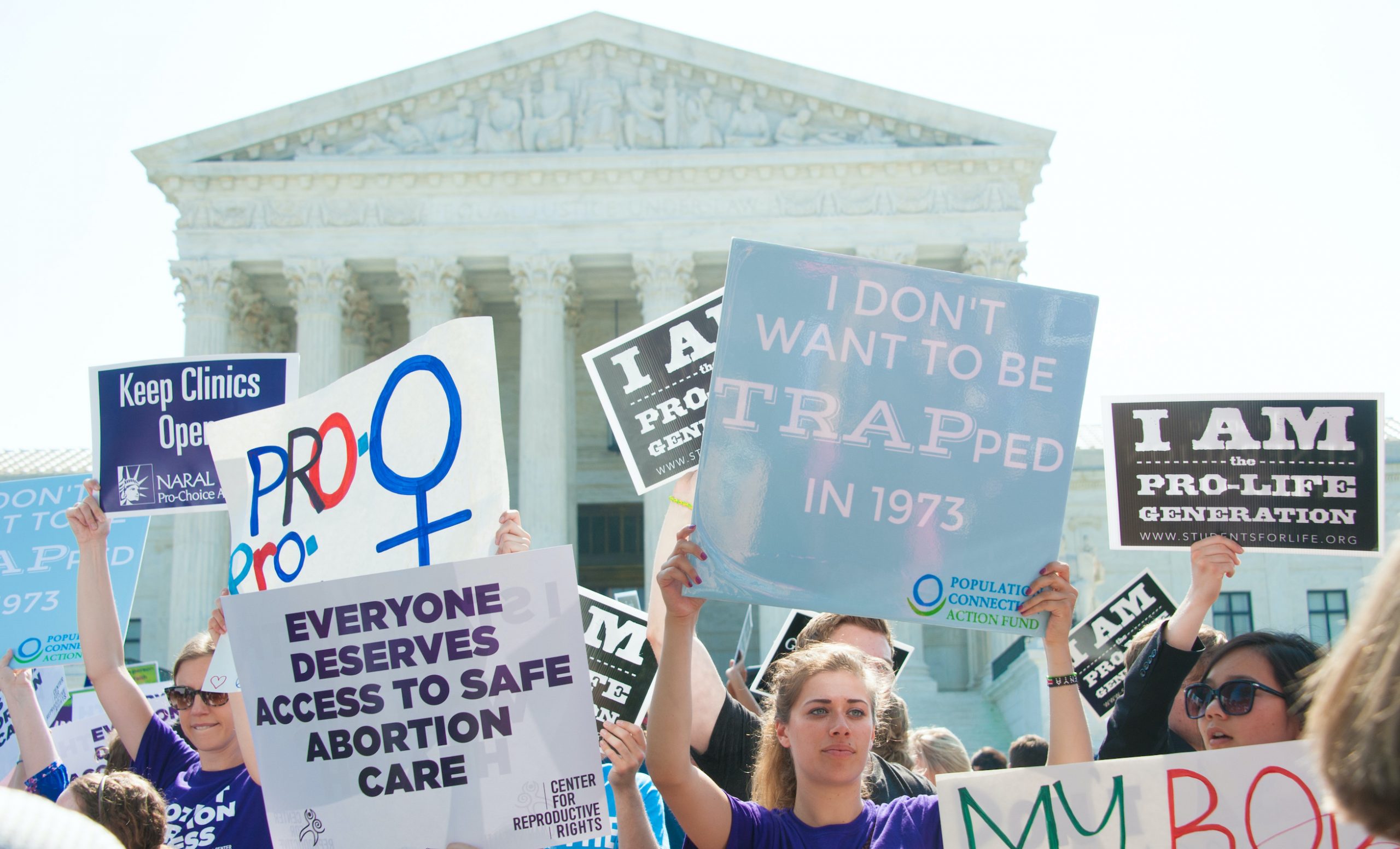 women holding signs in front of Supreme Court