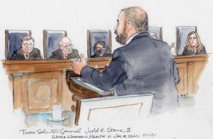 man with beard arguing at lectern and leaning forward, with several justices seated in background
