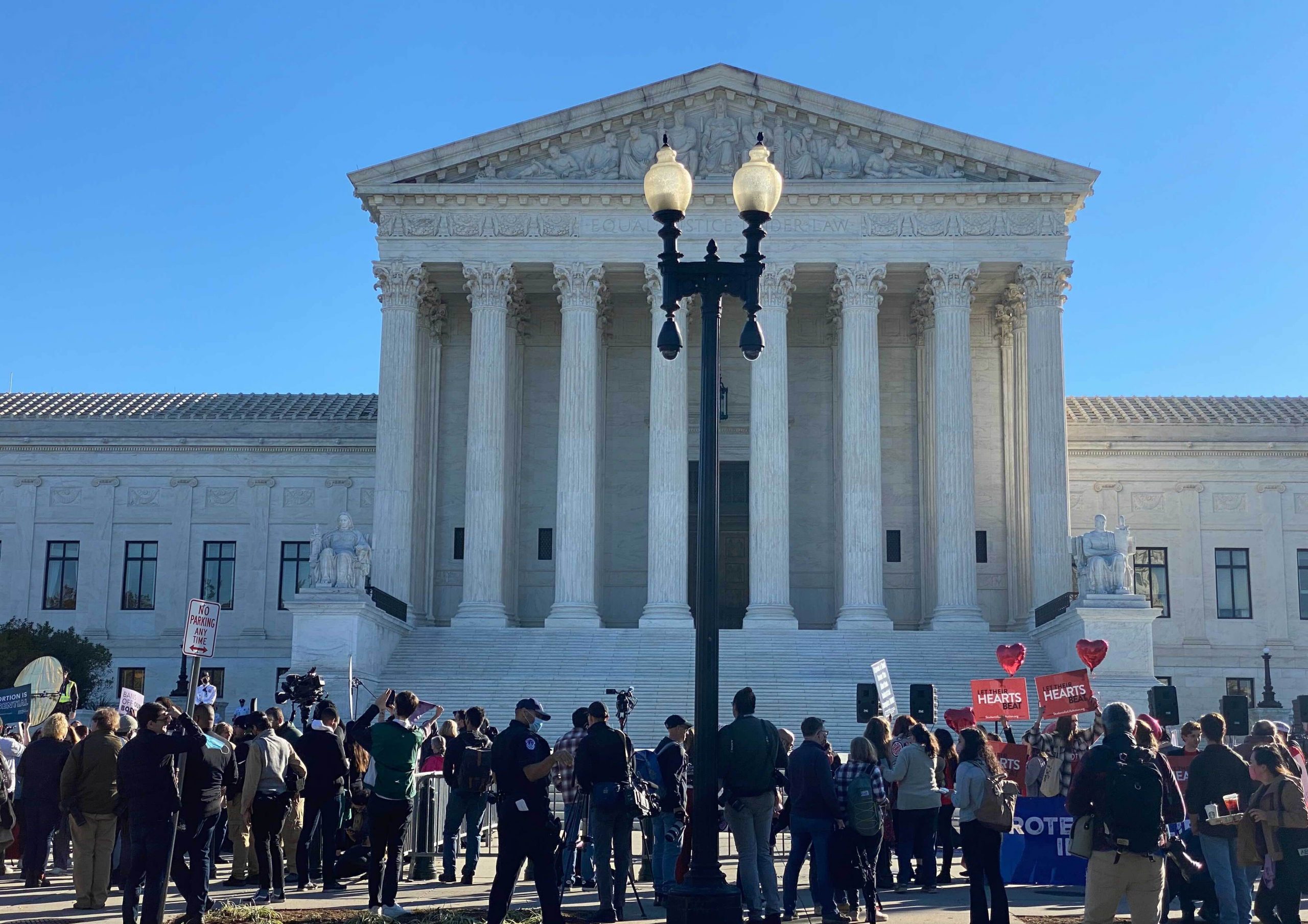 front of supreme court with crowd of people holding signs in foreground