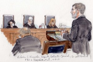 bearded man in glasses argues in front of three justices