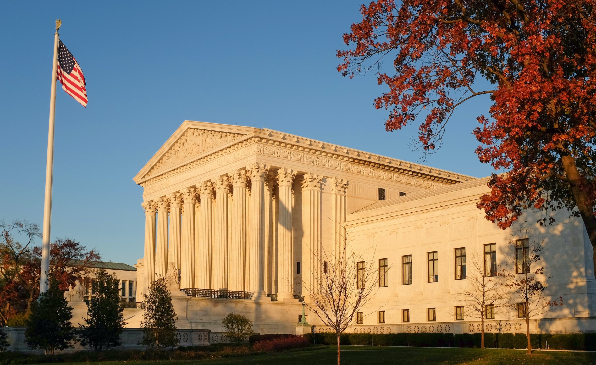 evening sunlight hitting the Supreme Court steps, flag pole, and fall tree