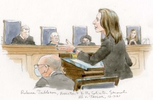 woman gesturing at lectern with justices listening in background