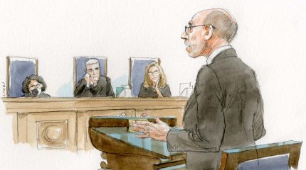 balding man with glasses arguing in front of three justices, some less amused than others