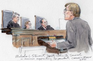 man in suit at lectern with three justices listening in background