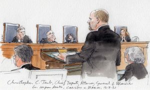 man in suit standing at lectern with four justices listening in background