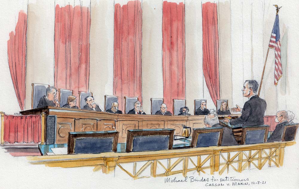 man standing at lectern with nine justices sitting on bench in backgroud