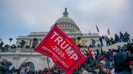 Trump 2020 flag flying as protestors cover Capitol steps