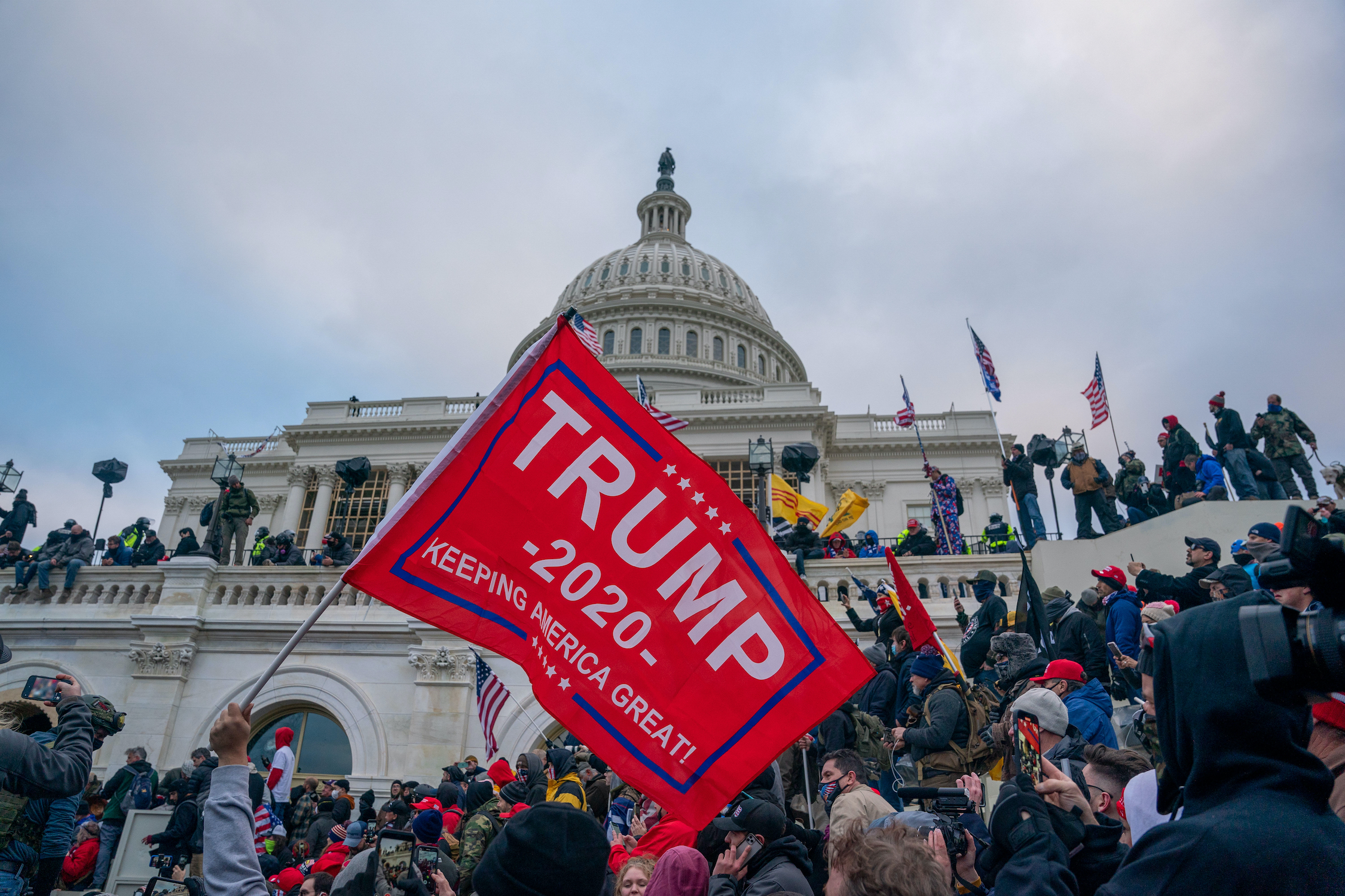 Trump 2020 flag flying as protestors cover Capitol steps