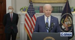 joe biden speaks at lectern while stephen breyer stands in background wearing mask