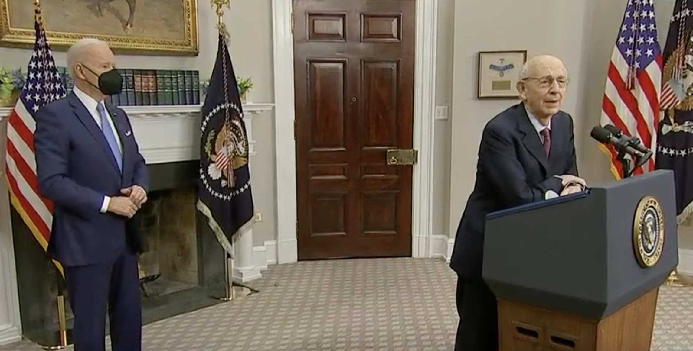 stephen breyer leaning on lectern while joe biden stands behind him wearing mask