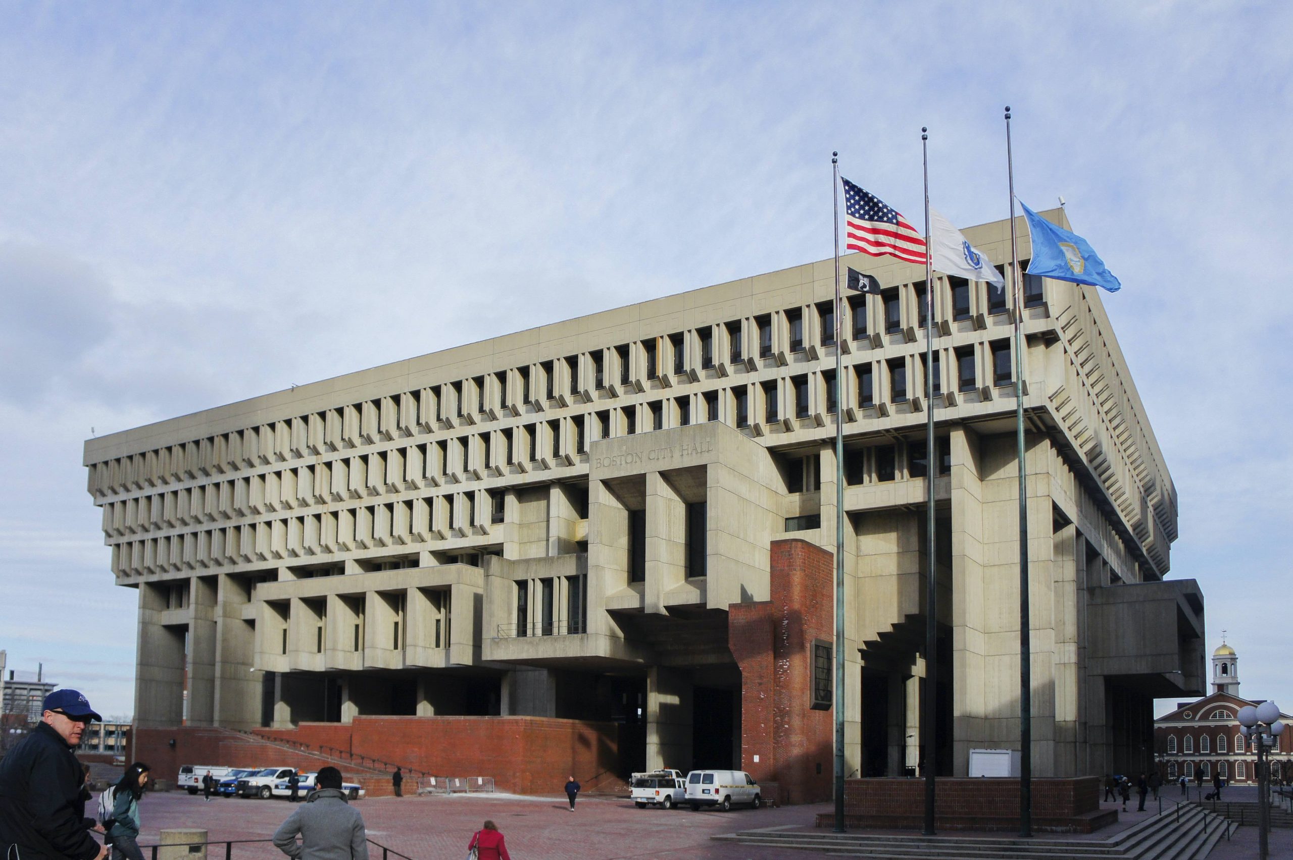 large cement building with three flagpoles in front