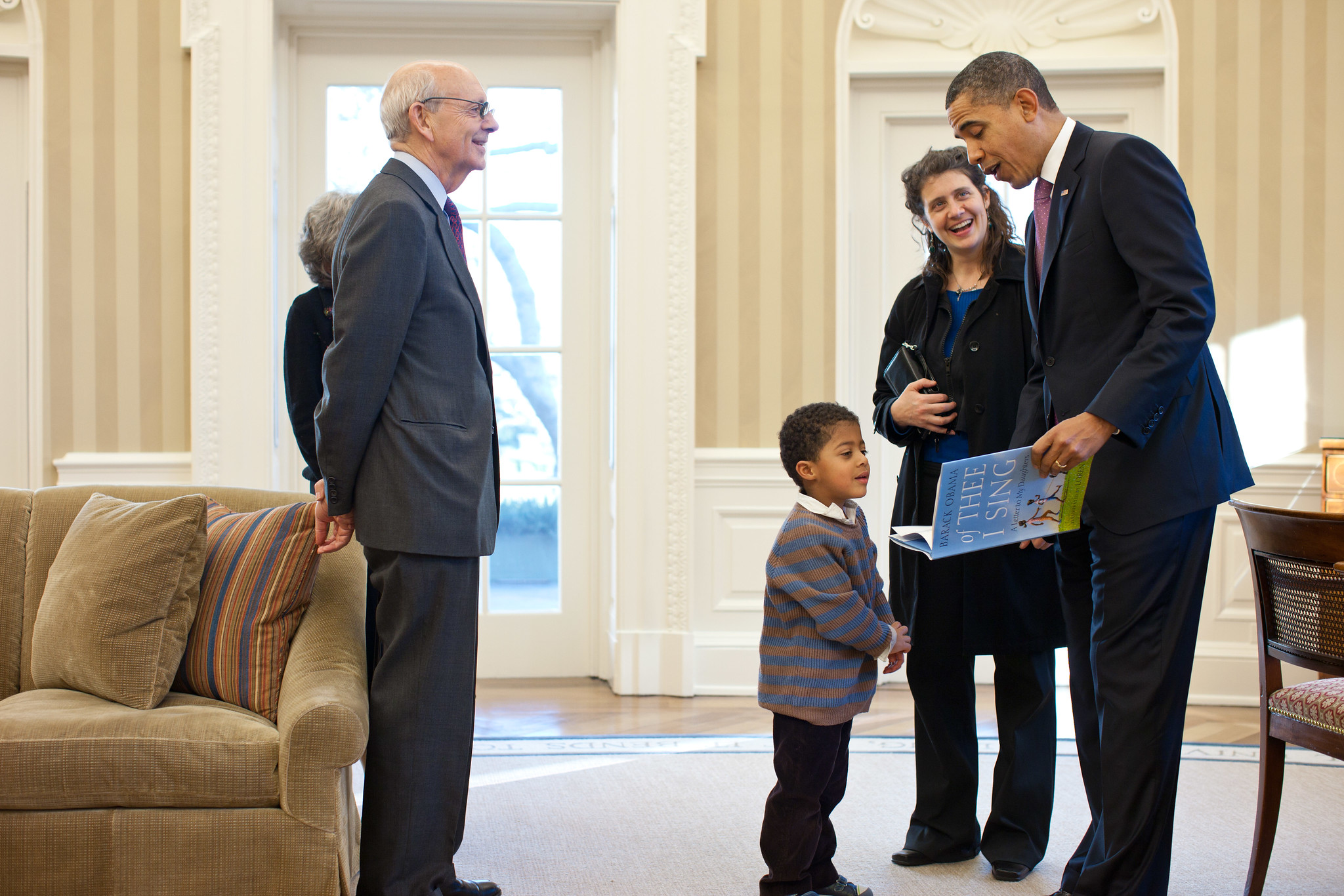 Justice Breyer looks on as president Obama shows a book to a young boy