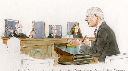 Man at podium talks to Justice Breyer who speaks with his hands