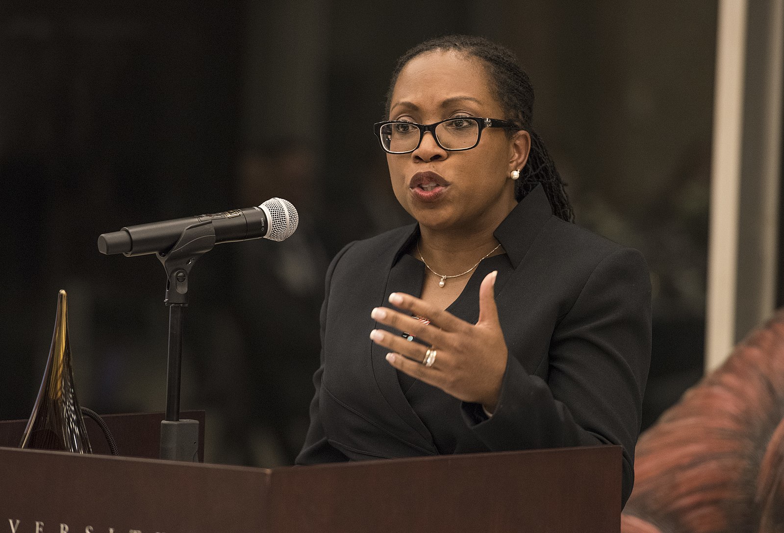 woman speaking at microphone while gesturing with left hand