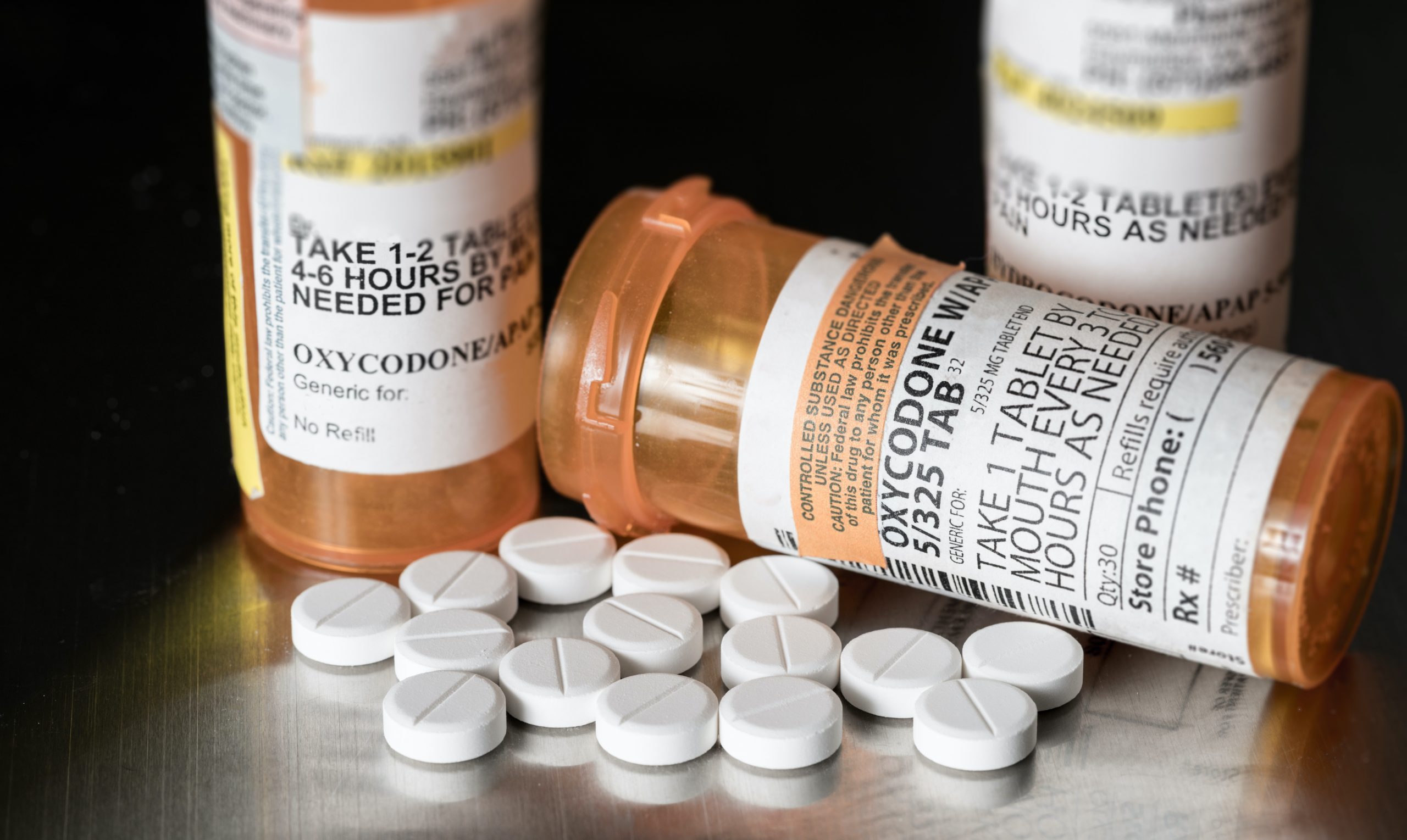 pill bottles bearing an oxycodone label, with pills lying on table