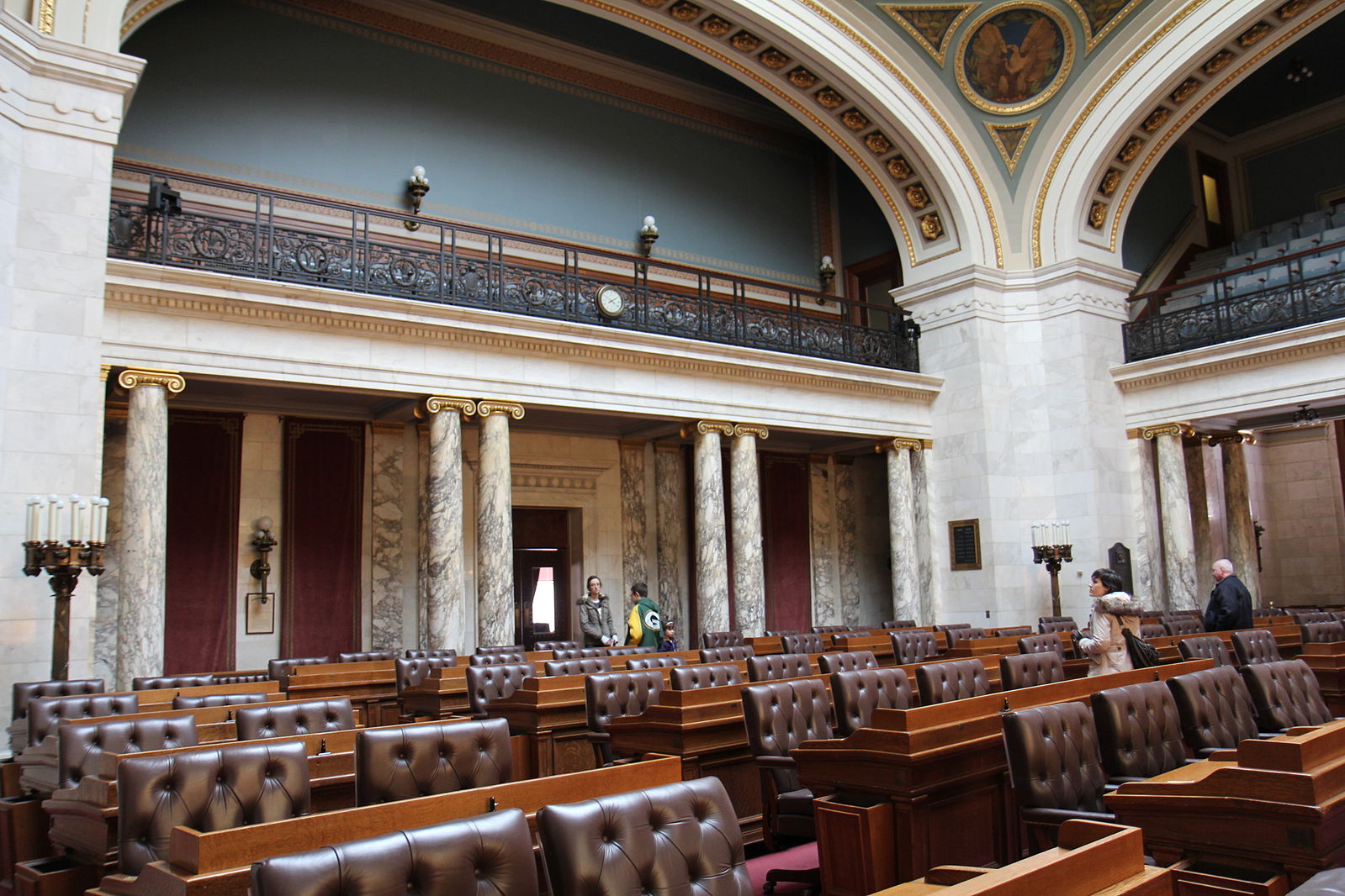 interior of large room with brown leather chairs and desks, and marble columns in back of room