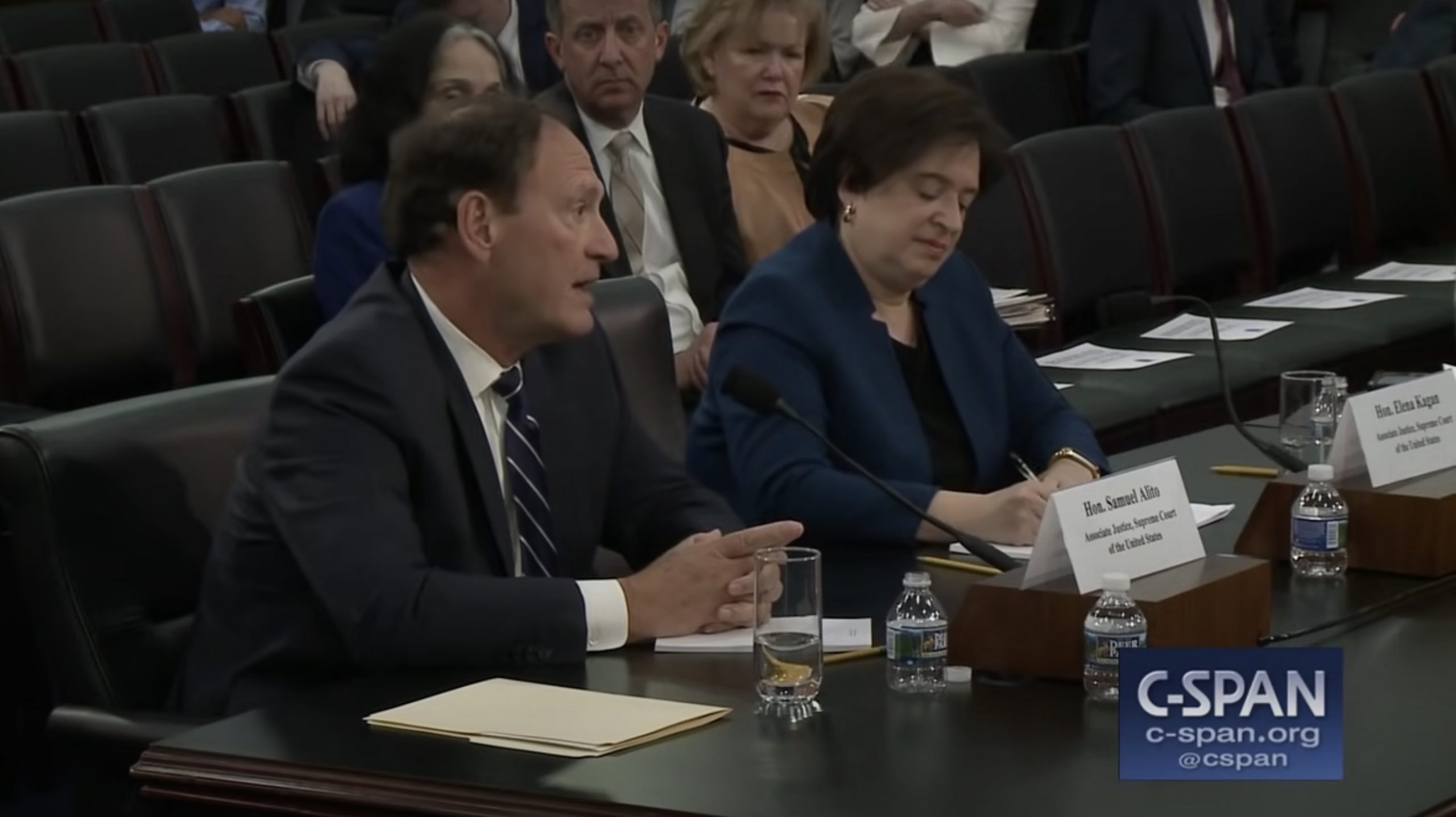 sam alito and elena kagan sitting at table in front of microphones