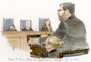 man in glasses argues before three contemplative justices