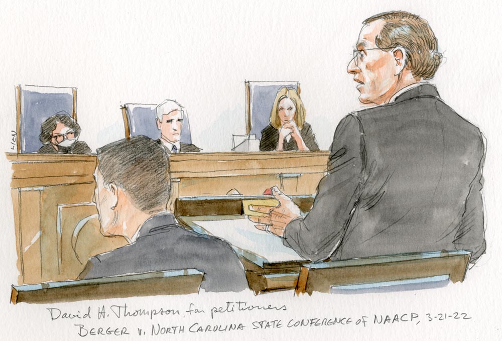 man in grey suit and glasses gestures as he argues at the lectern, in front of three seated justices