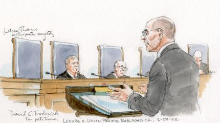 Man arguing in front of three justices and Justice Thomas' empty seat.