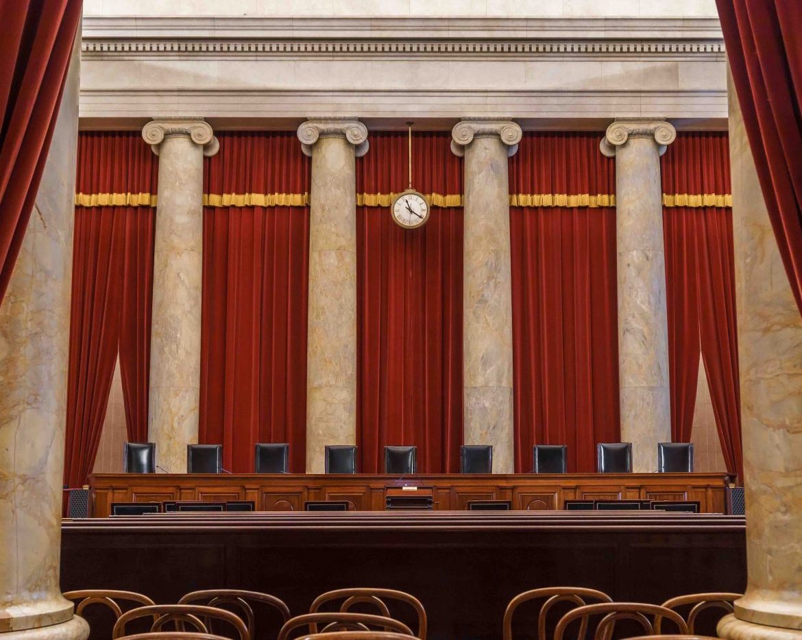 view of courtroom from rear, with large marble columns rising above the empty bench