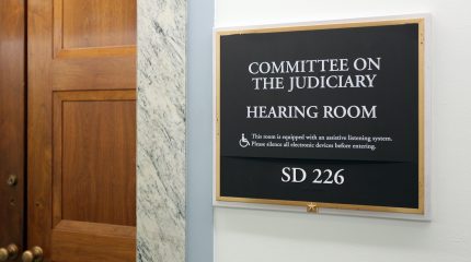 closed wooden door next to sign identifying room as Senate Judiciary Committee