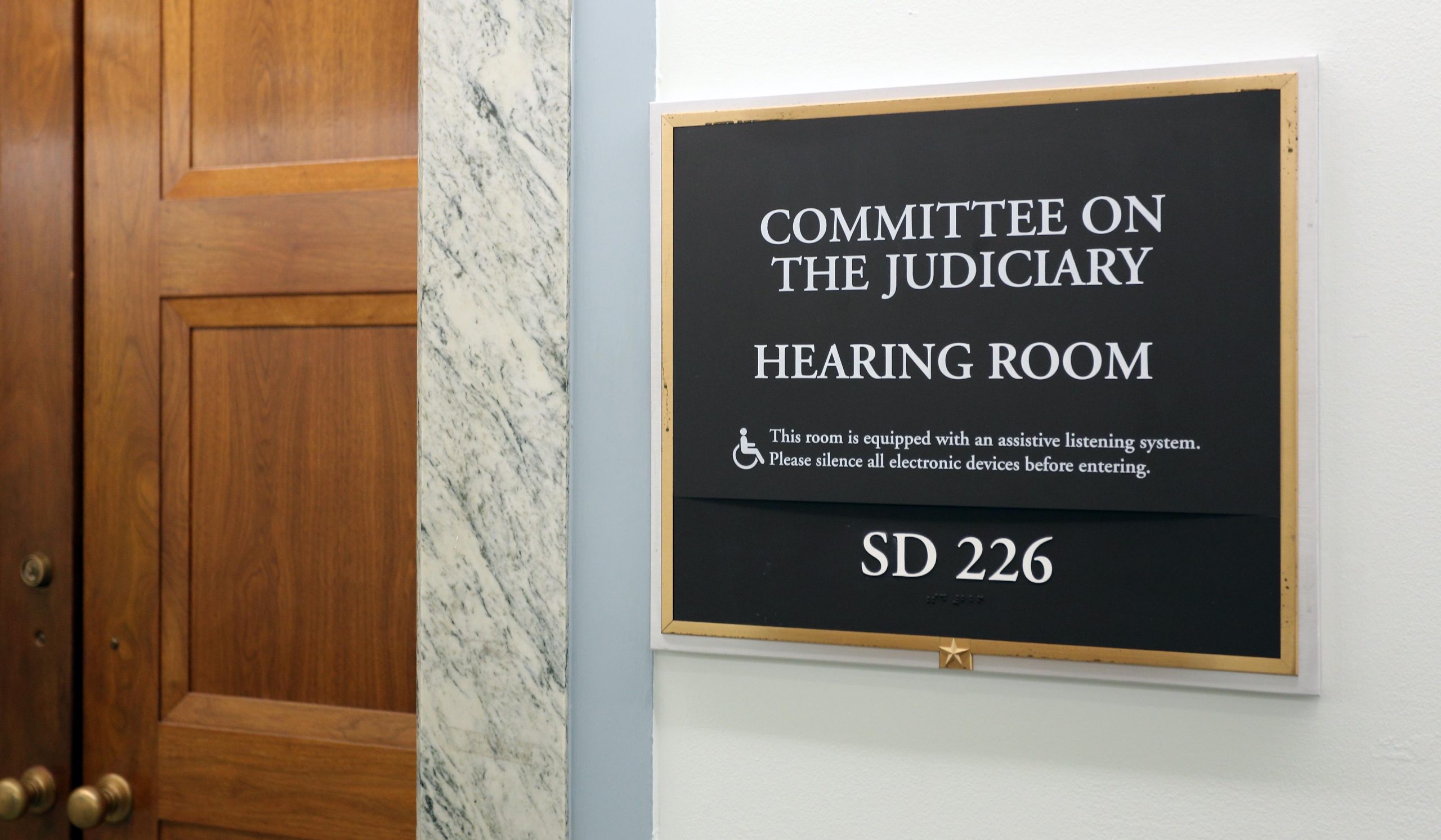 closed wooden door next to sign identifying room as Senate Judiciary Committee