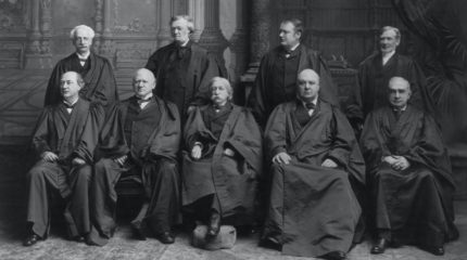 portrait of nine men posing for photo in judicial robes