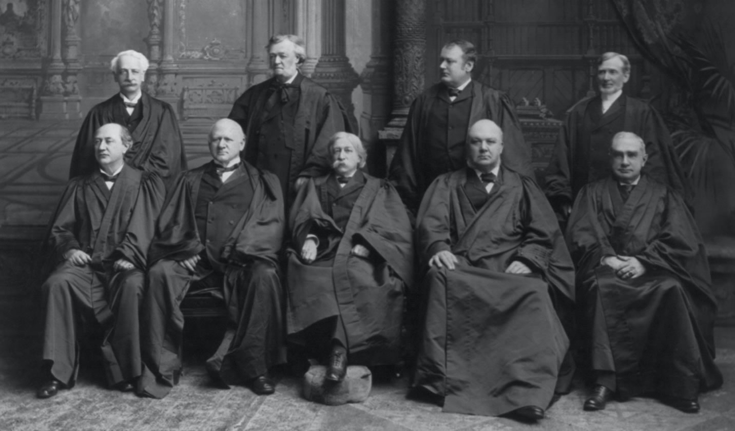 portrait of nine men posing for photo in judicial robes