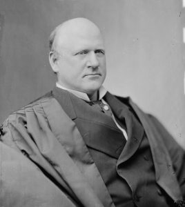 portrait of serious-looking bald clean-shaven man wearing judicial robe