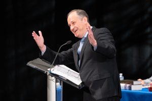 man with arms raised on podium