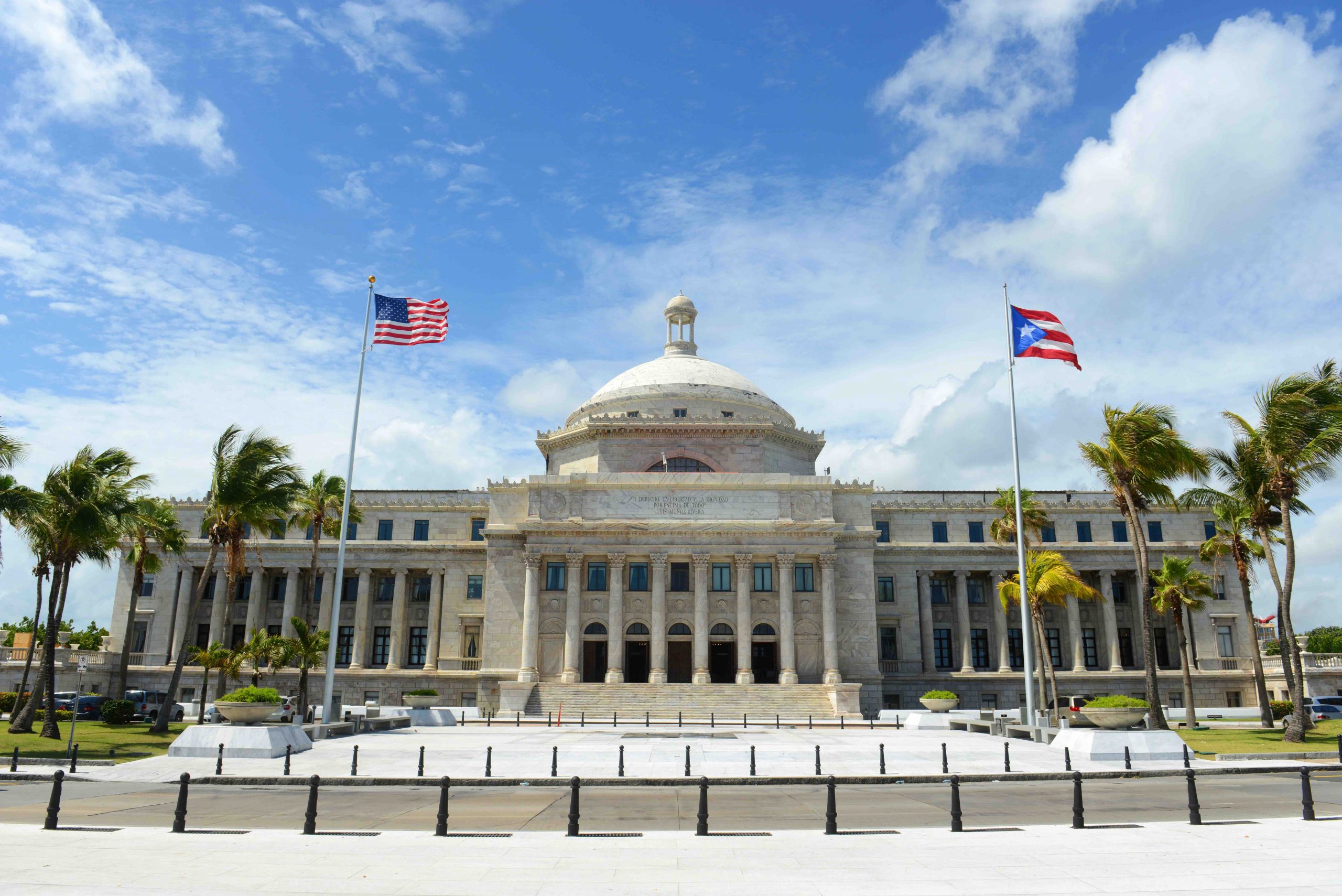 domed marble building with american flag and puerto rican flag flying in front