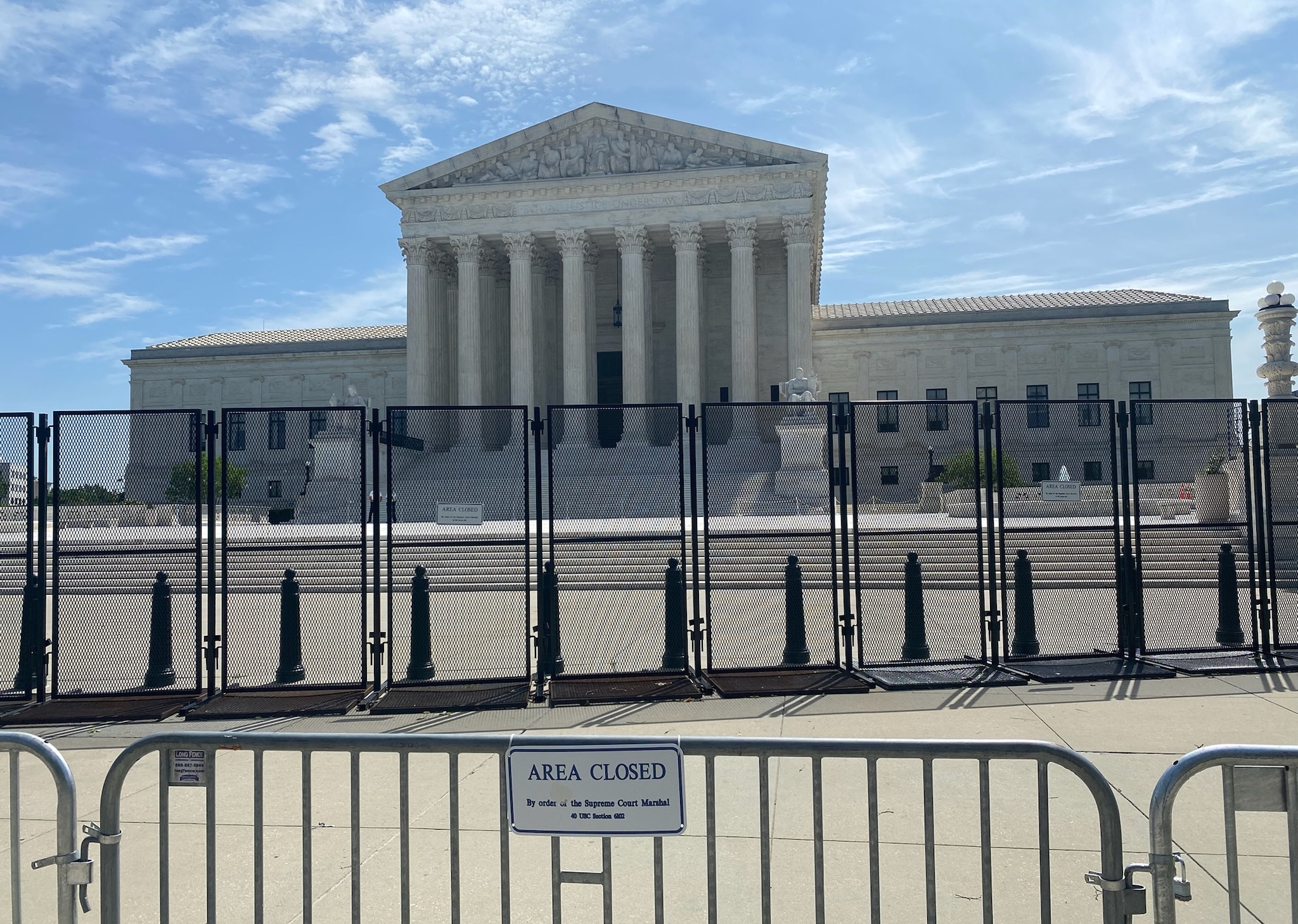 tall black fence and a gate bearing an "area closed" sign stand in front of the supreme court building