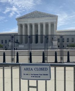 tall black fence and a gate bearing an "area closed" sign stand in front of the supreme court building