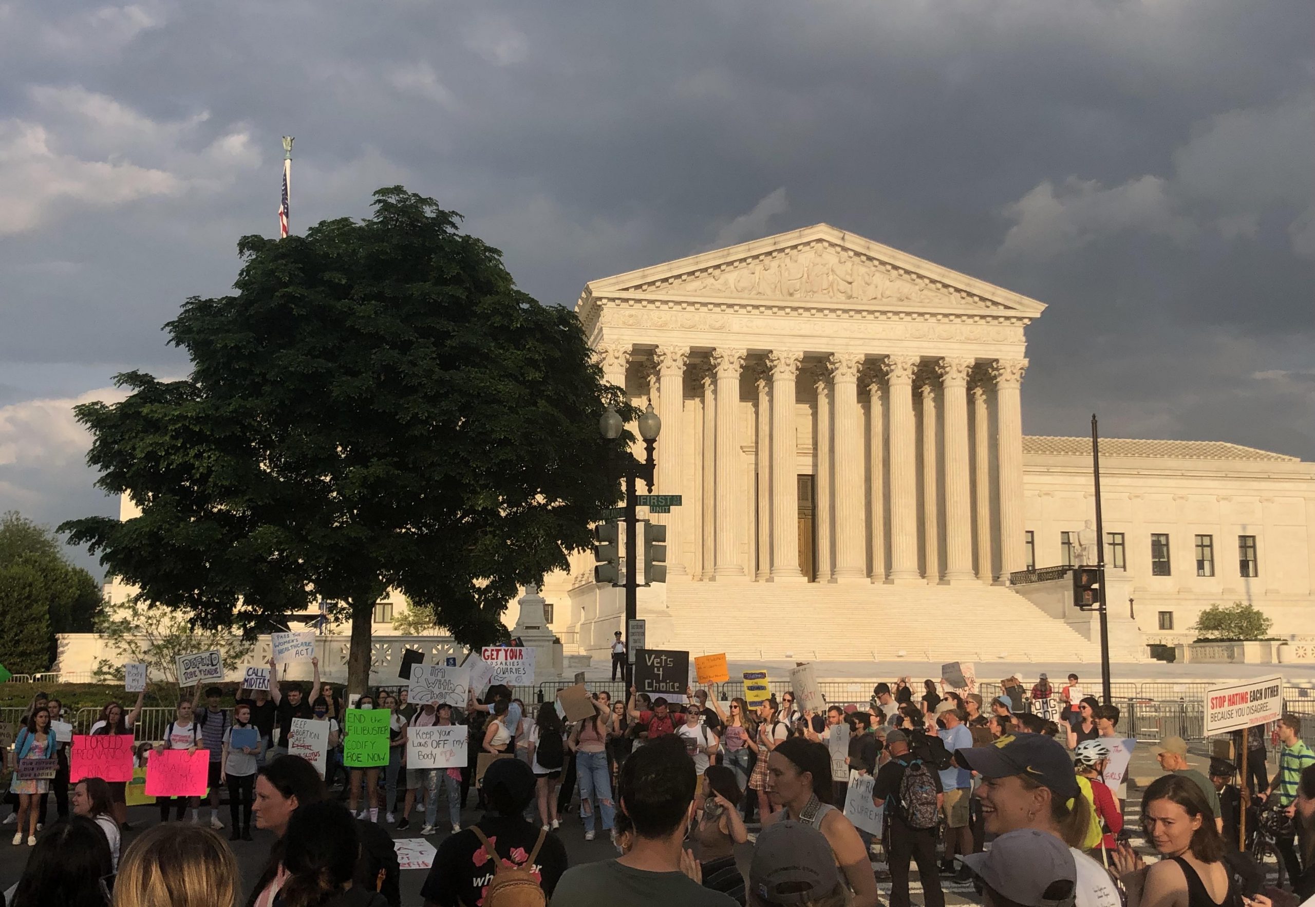 crowd of people stand in front of supreme court holding signs supporting abortion rights