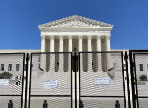 front facade of supreme court building with tall chain fence and "area closed" signs in foreground