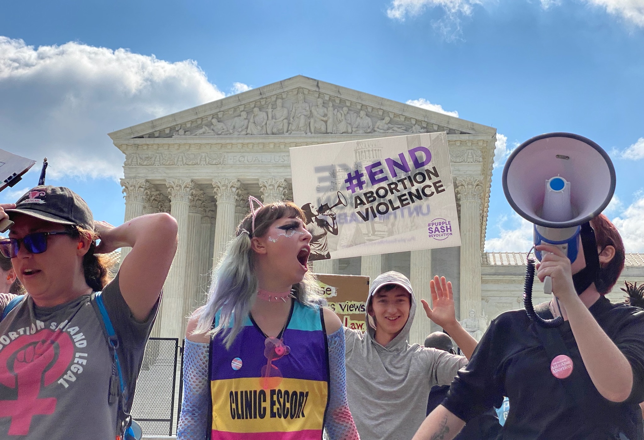 protesters shouting and holding signs in front of supreme court