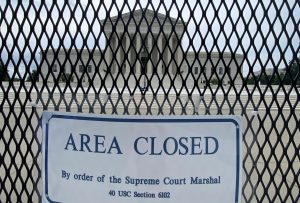 supreme court building seen in background through metal fence with "area closed" sign