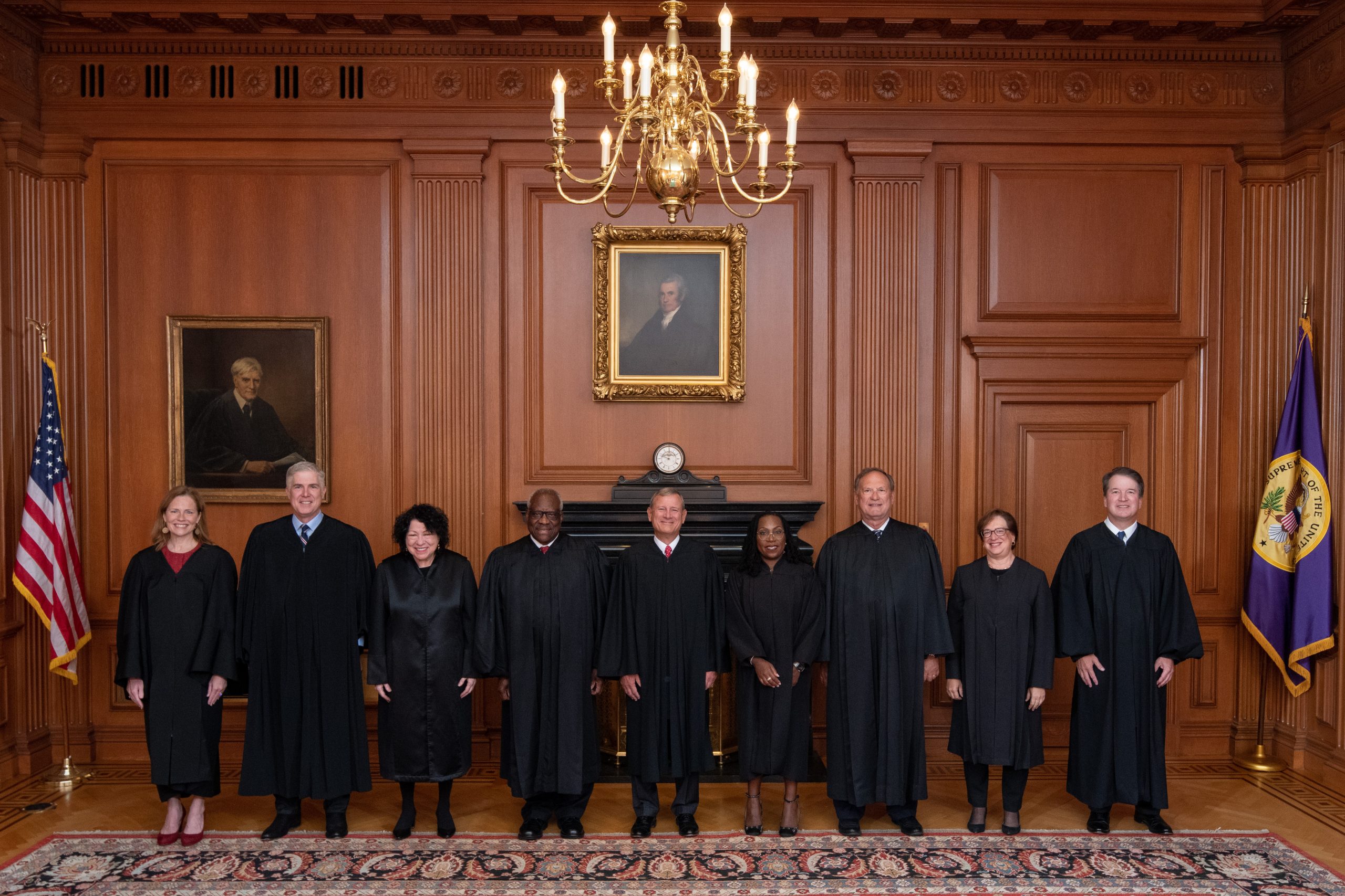 nine justices standing side by side, wearing black judicial robes.
